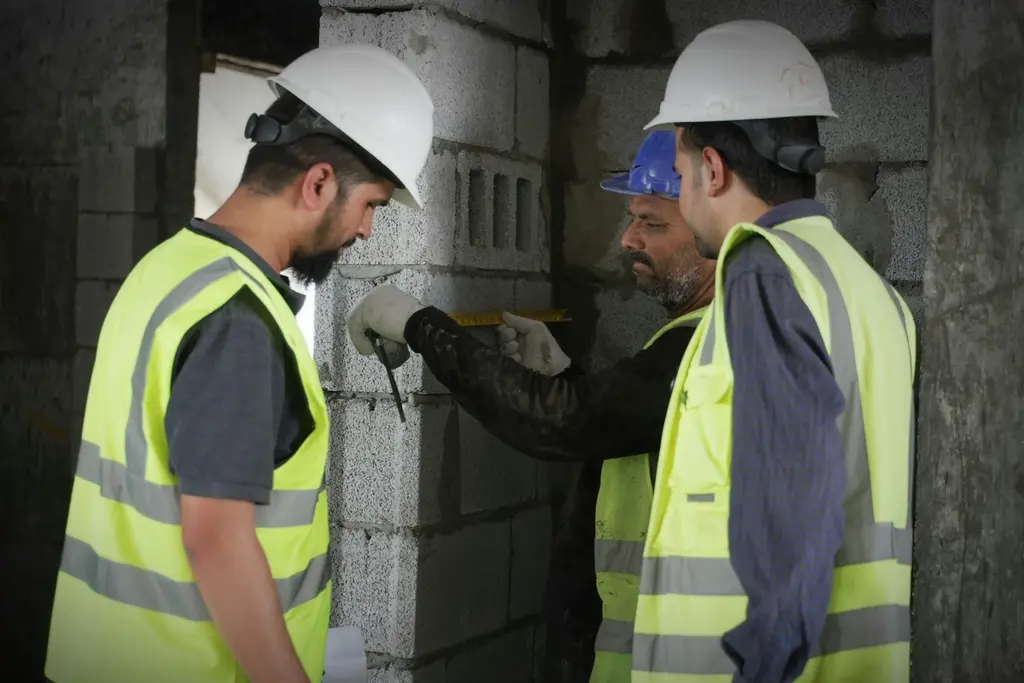 Two workers checking a block wall