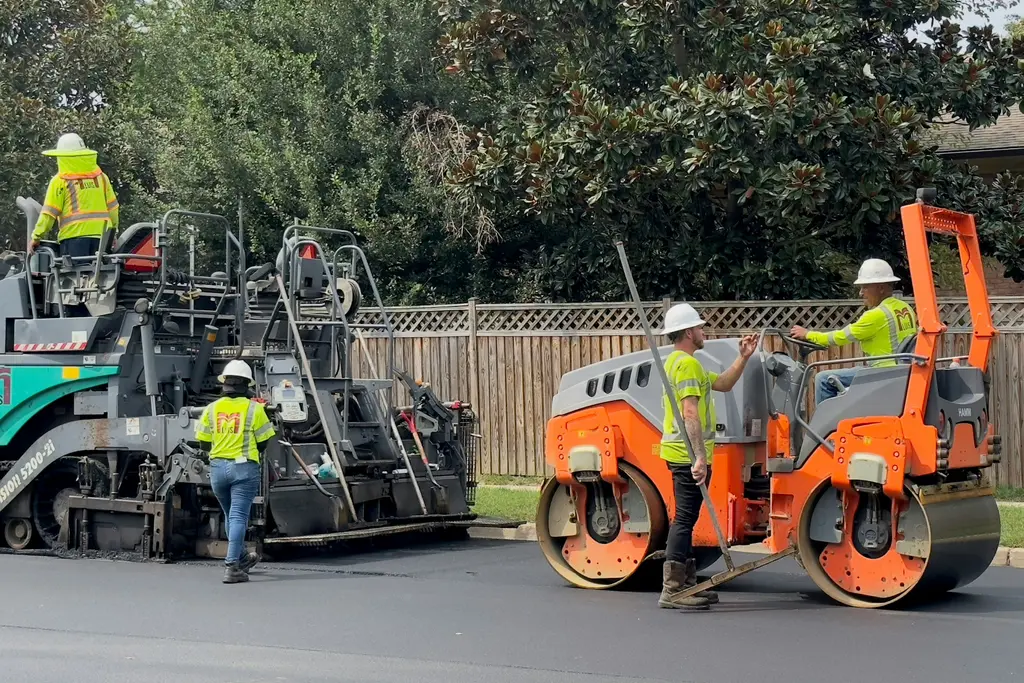 Paving crew running a paver and roller on a residential street