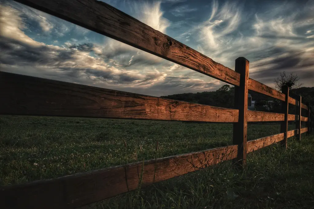 Wood ranch fence along a field at sunset